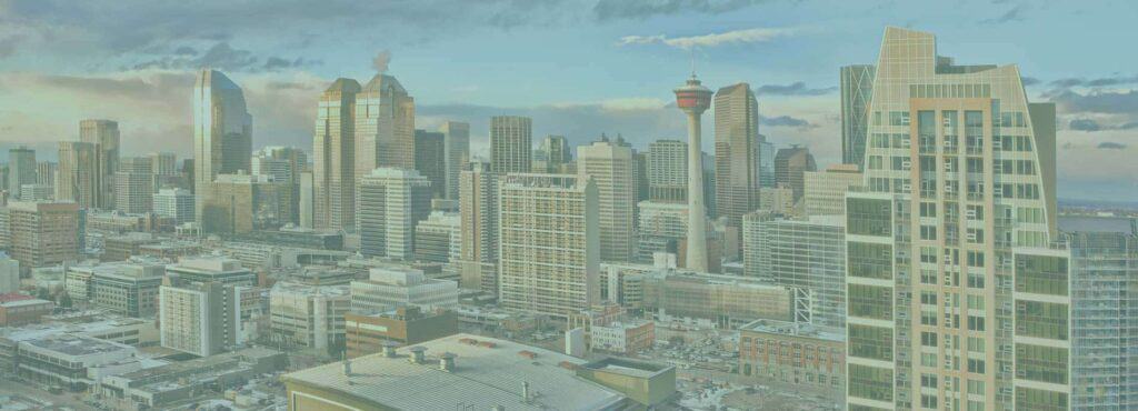 A city skyline with numerous tall buildings and skyscrapers under a partly cloudy sky, featuring a distinctive tower with a red top in the center—perfect inspiration for modern real estate web design. - Clio Websites | Top Canadian Web Design Company