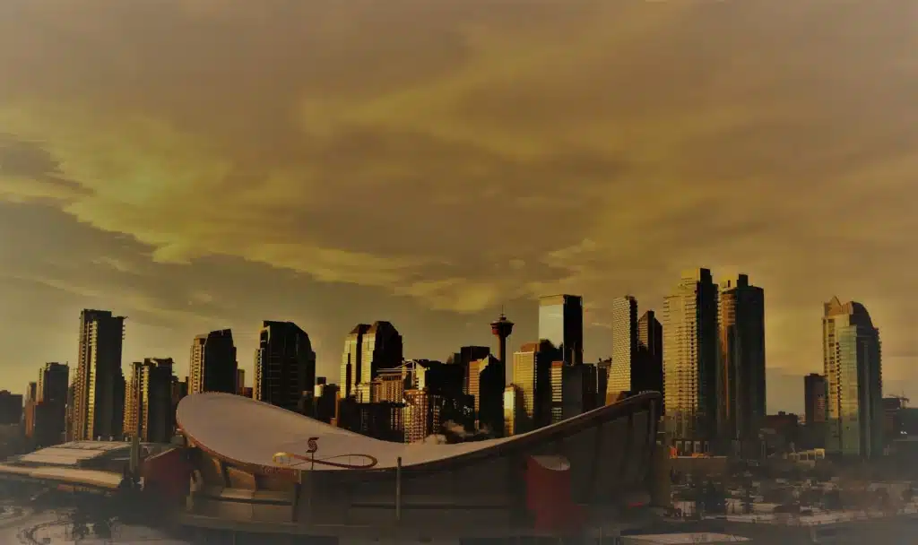 A city skyline at dusk with a prominent saddle-shaped building in the foreground. The skyscrapers are silhouetted against an orange-hued sky, creating a dramatic and warm atmosphere. - Clio Websites | Top Canadian Web Design Company